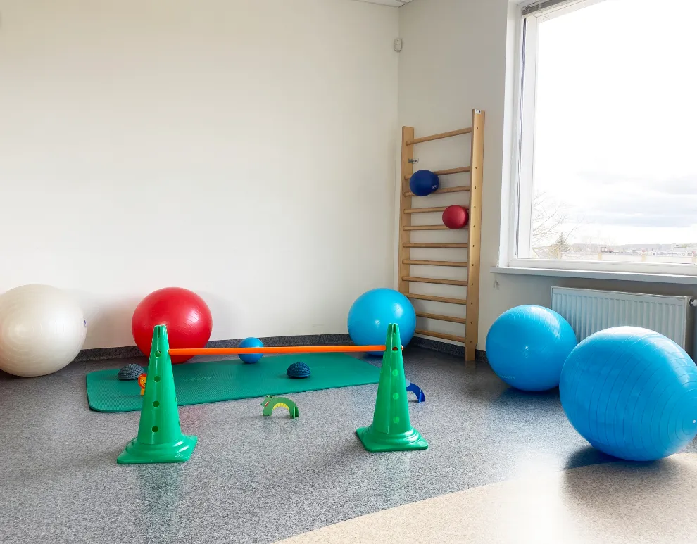 Kineziterapijos salė su kamuoliais ir gimnastikos sienele