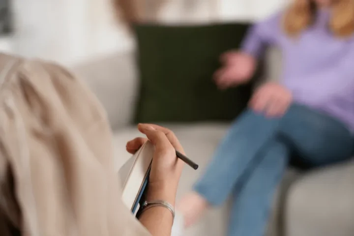 Psichologė konsultuoja pacientę ir užsirašo pastabas