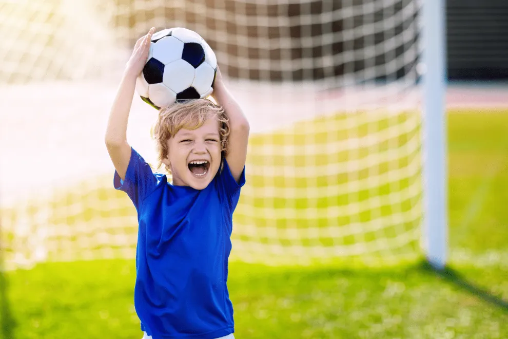 Berniukas su futbolo kamuoliu stovi prie vartų – sportuojančių vaikų sveikatos patikra
